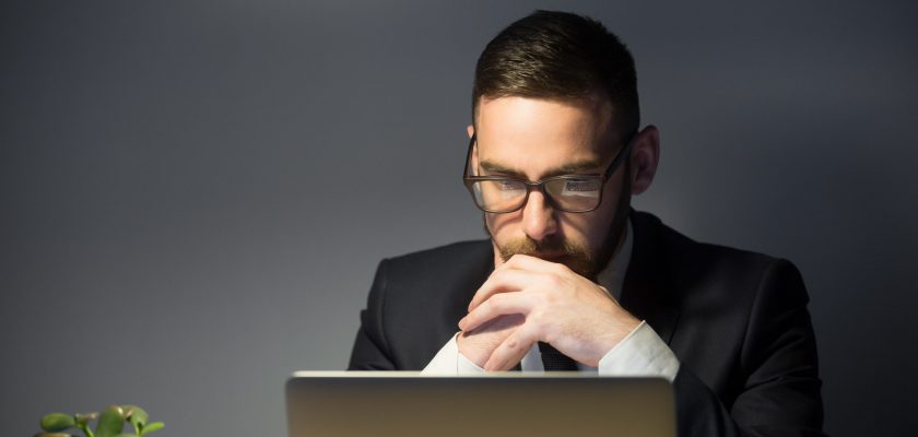 Concerned male thinking about company problem solution Concerned worker looking at laptop screen, thinking about problem solution, risks, company success strategies, person reading financial report. Concept of hardworking, concentration, making decision
