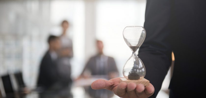 Businessman holding an hour glass, signifies the importance of being on time Businessman holding an hour glass, signifies the importance of being on time
